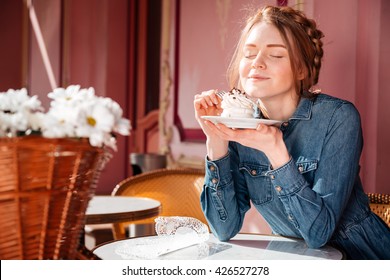 Happy cute young woman eating sweet tasty cupcake in outdoor cafe - Powered by Shutterstock