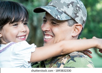 Happy Dad In Camouflage Uniform Holding Little Daughter In Arms, Hugging Girl Outdoors After Returning From Military Mission Trip. Closeup Shot. Family Reunion Or Returning Home Concept