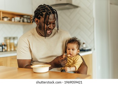 Happy dad feeding his baby daughter at home, portrait. - Powered by Shutterstock