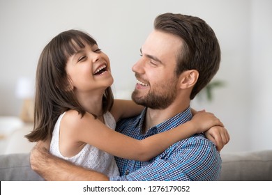 Happy Dad Holding Cute Cheerful Kid Daughter Laughing Enjoy Good Time Together, Loving Father And Smiling Little Girl Hugging, Caring Daddy Embracing Funny Child Relaxing Playing Having Fun Concept