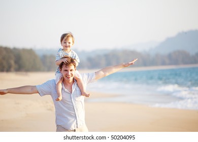 Happy Dad And Son Having Fun On The Beach