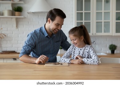 Happy Dad Teaching Excited Daughter Kid To Play Learning Board Game At Kitchen Table. Cheerful Girl Thinking Over Next Move In Checker Draughts, Training Brain Skills, Family Smart Activity Concept