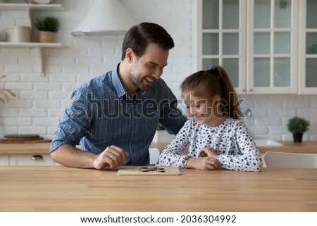 Happy dad teaching excited daughter kid to play learning board game at kitchen table. Cheerful girl thinking over next move in checker draughts, training brain skills, Family smart activity concept