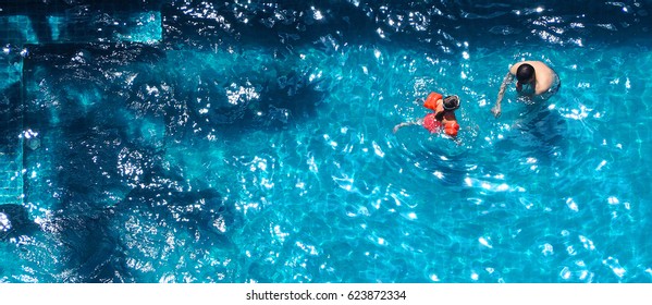 Happy Dad And Young Daughter Playing Together In Swimming Pool With Life Ring For Safety On Sunny Summer Day.