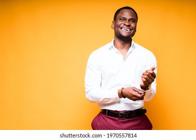 Happy dark-skinned man in white shirt going to work buttoning his sleeves and smiling - Powered by Shutterstock