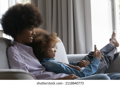 Happy Dating Black Teenage Couple In Love Using Smartphone And Having Fun At Home, Resting, Relaxing On Couch, Hugging, Making Video Call On Mobile Phone, Taking Selfie Together