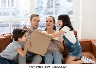 Happy Daughter And Brother With Parent Opening Gift Box. Smiling Siblings With Mom And Dad Surprised New Soft Toy On Birthday.