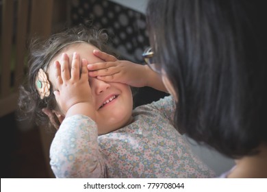 Happy Daughter Covering Her Eyes With Hands While Playing Peekaboo Game With Her Mother.