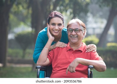 Happy daughter embracing grandfather sitting in a wheelchair at park
