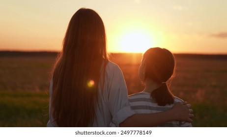 Happy daughter hugs mother outdoors. Child, girl hugging her mother in summer park in sun. Happy family on walk in field looking to future. Mom, child hugs together on sunny day. Carefree childhood - Powered by Shutterstock