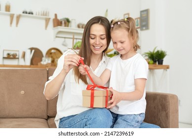 Happy daughter and mother open a gift and laugh at it. - Shutterstock ID 2147239619