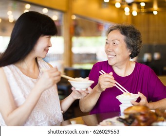 Happy  Daughter And Senior Mother Enjoy Eating In Restaurant
