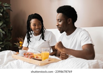 Happy delighted African American black couple lying in bed holding tray with tasty breakfast smiling at camera happy morning at weekends. - Powered by Shutterstock