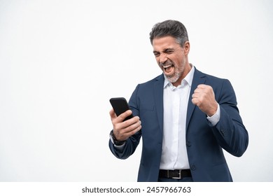 Happy delighted satisfied business man looking at mobile phone screen gesturing yes winning pose, isolated background. Overjoyed excited businessman in suit make winner gesture reading happy good news - Powered by Shutterstock