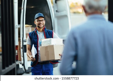 Happy deliverer carrying packages while making home delivery to his customer.  - Shutterstock ID 1558877723