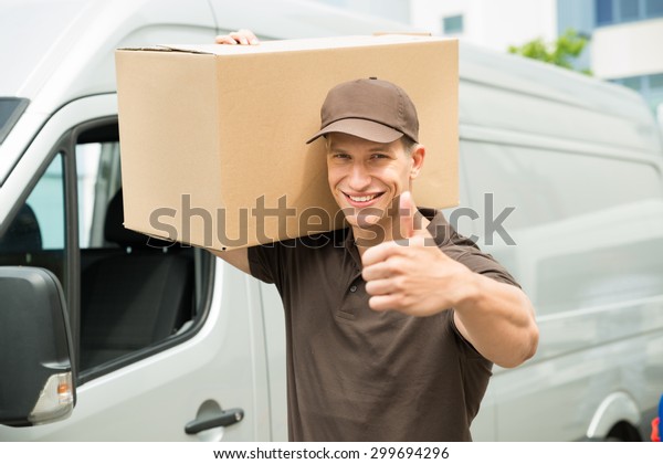 Happy Delivery Man Carrying Cardboard Boxes Showing\
Thumbs up Sign