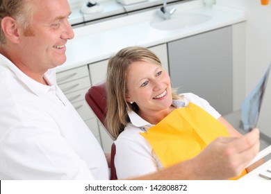 Happy Dentist And Female Patient Analyzing Xray In Clinic