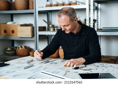 Happy Designer Working on a Project in his Office. 
Smiling furniture designer sketching drawing design of plant stand at his workplace.