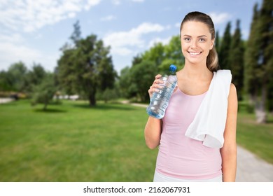 Happy Determined Athlete, Beautiful Woman Stands On A City And Drinks Water, Resting After Early Morning Jog At Sunrise