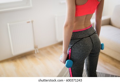 Happy determined woman working out with dumbbells at home