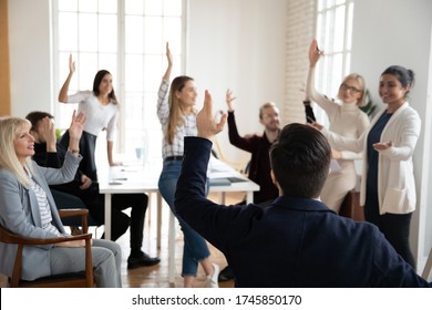 Happy Different Ages Business People Raising Hands, Having Questions To Smiling Indian Speaker After Workshop Finish. Excited Middle Aged And Young Board Members Voting For Decision At Workplace.