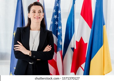 Happy Diplomat Standing With Crossed Arms Near Flags 