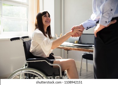 Happy Disabled Businesswoman Sitting On Wheelchair Shaking Hand With Her Partner - Powered by Shutterstock