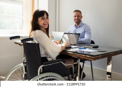 Happy Disabled Businesswoman Working On Laptop With Her Partner