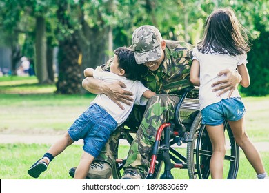 Happy disabled military man in wheelchair returning home and hugging kids. Veteran of war or family reunion concept - Shutterstock ID 1893830659