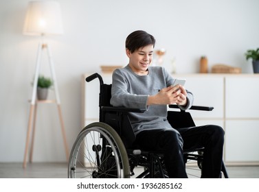 Happy Disabled Teen In Wheelchair Using Digital Tablet At Home, Browsing Internet Or Watching Videos, Copy Space