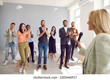 Happy Diverse Audience Giving Young Woman Standing Ovation. Satisfied Adult Multiracial Male And Female Attendees Stand Up And Applaud Speaker After Interesting Speech And Educational Business Lecture