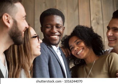 Happy diverse black and white people group with smiling faces bonding together, cheerful african and caucasian young multi ethnic friends having fun laughing embracing, multiracial friendship concept