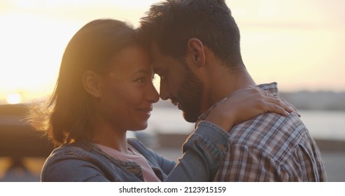 Happy diverse boyfriend and girlfriend hug enjoying spending time together outdoors. Close up of multiethnic romantic couple embrace outdoors on sunset sky background - Shutterstock ID 2123915159