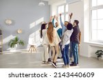 Happy diverse business team celebrating success and having fun all together. Group of cheerful ecstatic people standing in circle in modern office high five each other and shout Yes we did it, Hooray