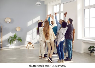 Happy diverse business team celebrating success and having fun all together. Group of cheerful ecstatic people standing in circle in modern office high five each other and shout Yes we did it, Hooray