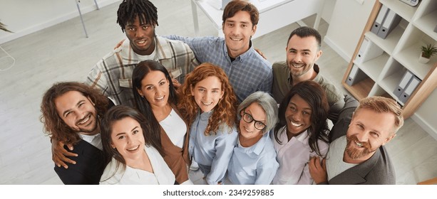 Happy diverse business team at work in office. Top view high angle shot from above group portrait of young and senior multiracial multiethnic people standing together, looking up at camera and smiling - Powered by Shutterstock