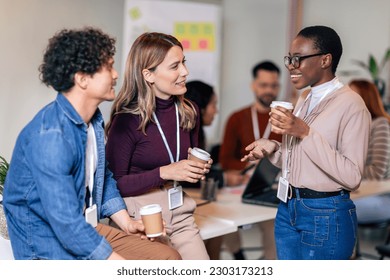 Happy diverse colleagues have fun at lunch break in office, smiling multiracial employees laugh and talk  drinking coffee