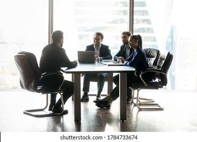 Happy Diverse Colleagues Hr Team Sitting At Table In Front Of Male Candidate, Enjoying Holding Job Interview In Office. Full Length Motivated Male Seeker Making Good First Impression On Employers.