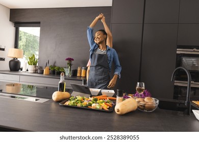 Happy diverse couple in aprons preparing meal having fun dancing in kitchen. Food, cooking, togetherness, relationship, fun, romance, lifestyle and domestic life, unaltered. - Powered by Shutterstock