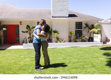 Happy Diverse Couple Embracing In Front Of House On Sunny Garden Terrace. Staying At Home In Isolation During Quarantine Lockdown.