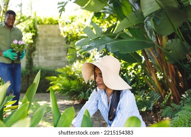 Happy Diverse Couple Gardening Together, Planting Flowers In Sunny Garden. Happiness, Health, Domestic Life And Inclusivity Concept.