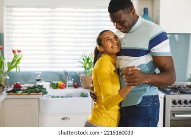 Happy diverse couple having fun slow dancing and smiling at each other in kitchen. Happiness, domestic life, love and inclusivity concept. - Powered by Shutterstock