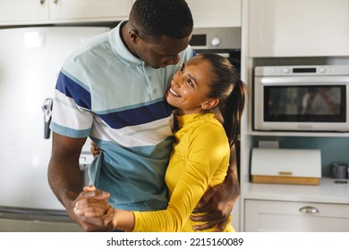 Happy diverse couple having fun slow dancing and smiling at each other in kitchen. Happiness, domestic life, love and inclusivity concept. - Powered by Shutterstock