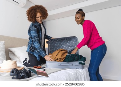 Happy diverse couple packing suitcase together in bedroom, at home. Travel, vacations, preparation, lifestyle and free time, unaltered. - Powered by Shutterstock