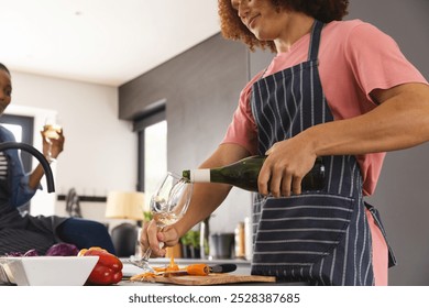 Happy diverse couple preparing meal and drinking wine in kitchen. Food, cooking, togetherness, relationship, lifestyle and domestic life, unaltered. - Powered by Shutterstock