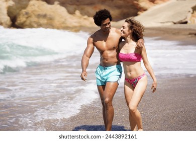 Happy diverse couple walking on beach near sea - Powered by Shutterstock