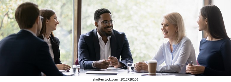 Happy diverse different aged business team discussing work  Leader   employees talking in office meeting room together  brainstorming  sharing ideas   solutions  negotiating project 