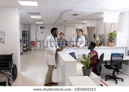 Happy diverse doctors and medical staff talking at reception desk of hospital ward, copy space. Hospital, teamwork, medical and healthcare services.