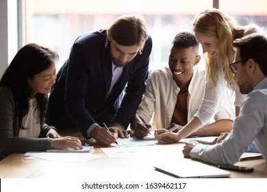 Happy diverse employees working with documents together, reading project statistics, smiling colleagues engaged in teamwork, developing strategy at corporate meeting, talking, brainstorming - Shutterstock ID 1639462117