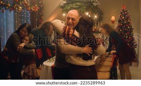 Happy diverse family meeting each other at cozy home for celebrating Christmas or New Year. They hugging, talking and smiling. Setting table with dishes. Holidays decorations and Christmas Tree.